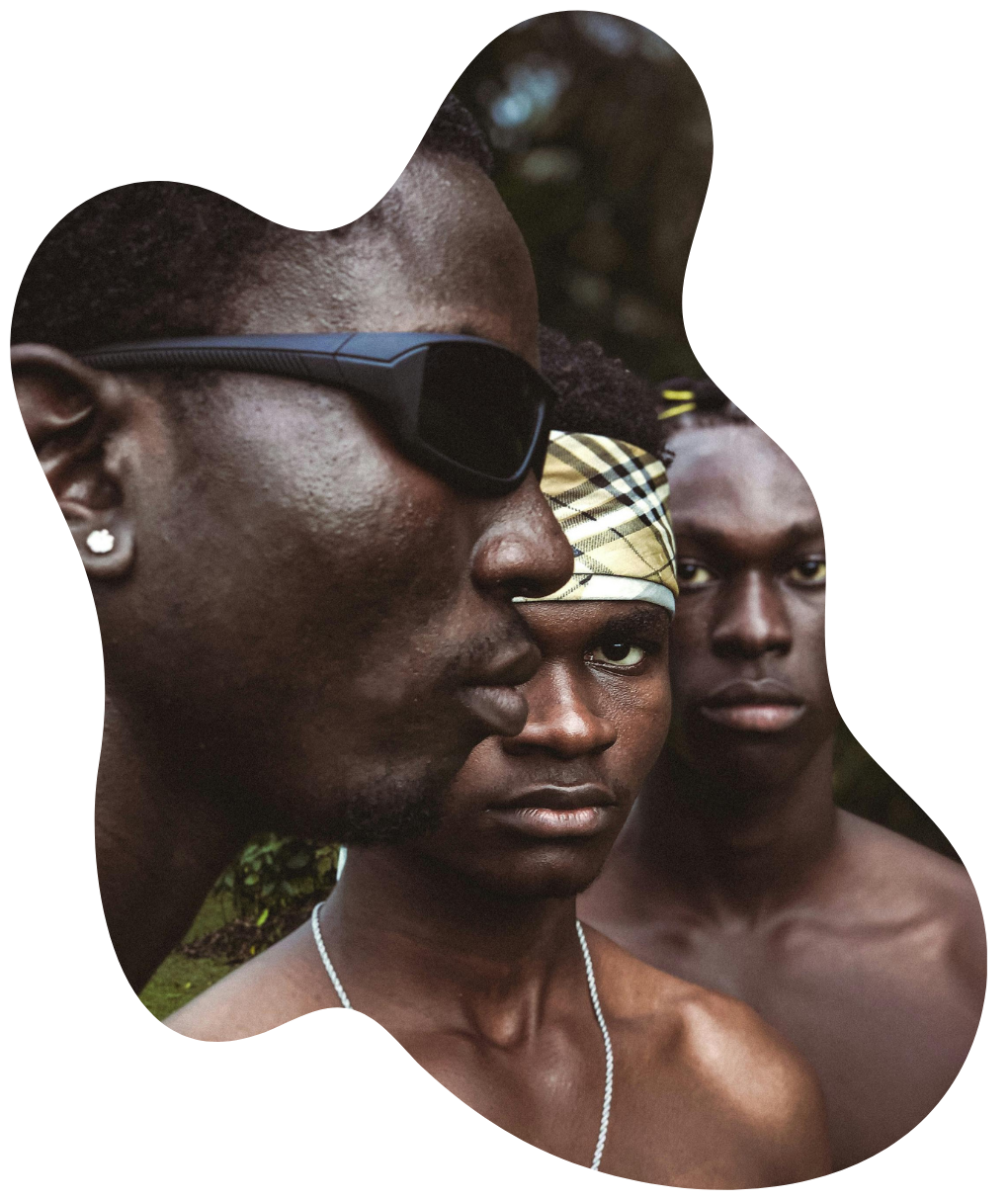 Three Black men standing together in natural light, wearing expressive accessories and intense expressions — a portrait of strength, identity, and solidarity.